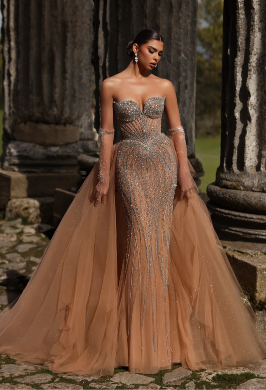 Elegant and luxurious dress adorned with sparkling crystals and gemstones, featuring a long back piece and long sleeves with cuffs.