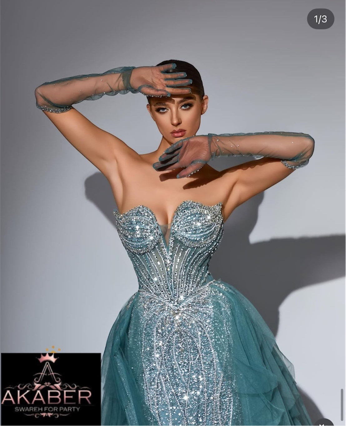 Elegant and luxurious dress adorned with sparkling crystals and gemstones, featuring a long back piece and long sleeves with cuffs.